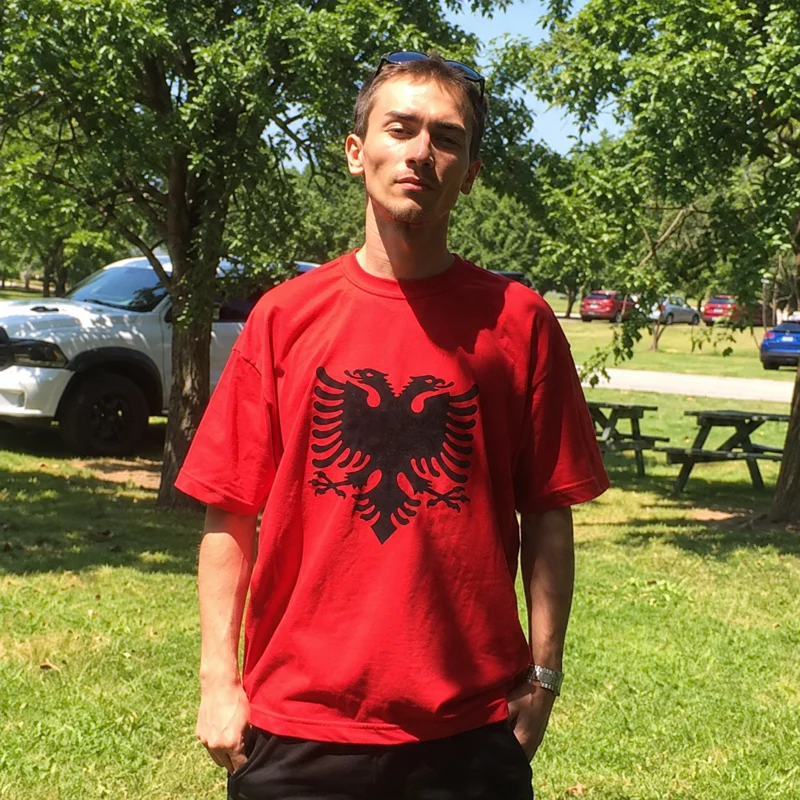 D-Prave wearing a red T-shirt with a black Albanian double-headed eagle